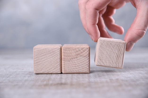 Hand zet lege houten kubus op de tafel