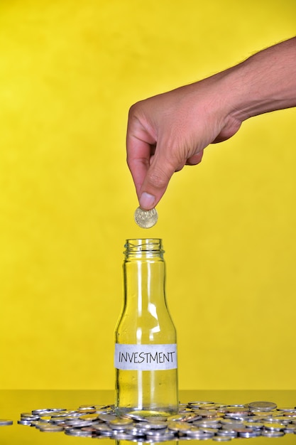 Hand zet munt in fles met woord Investering - Financieel Concept