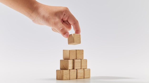 Hand zetten houten kubussen gerangschikt in de vorm van de piramide op wit