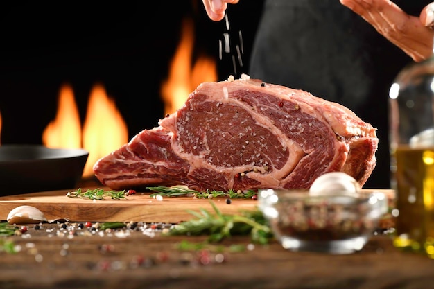 Handbestrooiing van zout en kruiden op rauw Ribeye steak vlees rundvlees