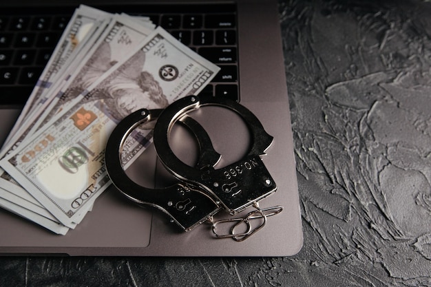 Handboeien en dollarbankbiljetten op een laptop toetsenbord Online fraudeconcept