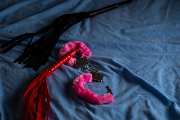Handboeien met rode vacht en een zweep Apparaten voor liefdesspelletjes op het bed