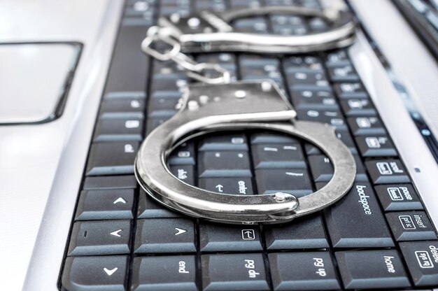 Foto handboeien op het toetsenbord van de laptop cybercriminaliteit concept close-up