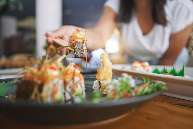 Handclose-up en eetstokjes in sushi-restaurant voor lekker eten en feesten met cateringschotel Persoon gezonde vis en zalm met traditionele cultuur of fastfood in eetbar of winkel