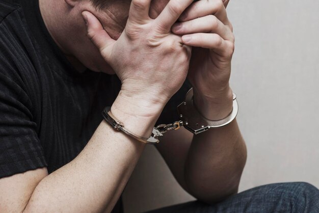 Photo handcuffed man covering his face with his hands