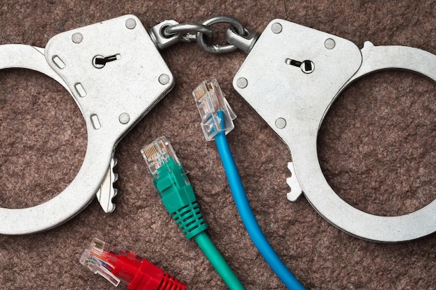 Photo handcuffs and computer wires concept on the theme of punishment in the field of computer crimes