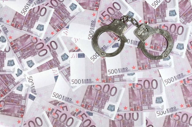 Handcuffs on five hundred euros background. Financial crime, dirty money and corruption concept - 500 money bills and dirty steel handcuffs