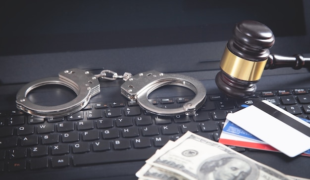 Foto manette, martelletto, carta di credito, soldi sulla tastiera del laptop. concetto di criminalità informatica e frode online