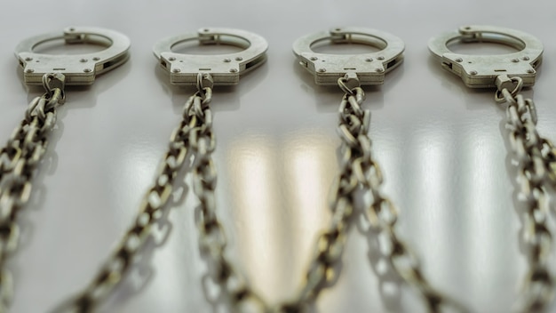 The handcuffs hang in a row on a chain on the wall Selective focus