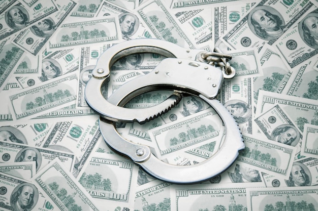 Handcuffs over stack of dollar banknotes