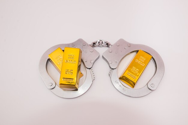 Handcuffs and three gold bars on a white background.