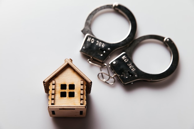 Photo handcuffs and wooden house real estate and fraud