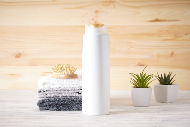 Foto handdoek, haarborstel, shampoo en vetplanten op een houten ondergrond