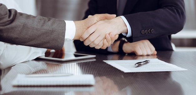 Handdruk als succesvolle onderhandeling die close-up beëindigt Onbekende zakenmensen schudden handen na contractondertekening in modern kantoor