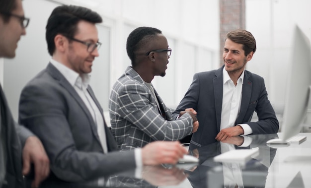 Handdruk van jonge zakenpartners aan de kantoortafel het concept van samenwerking