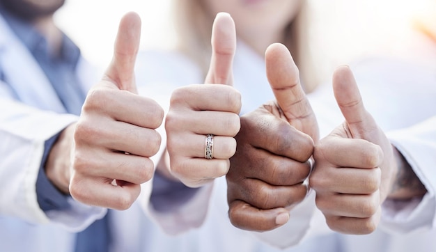 Handen artsen en duimen omhoog samen in close-up voor motivatieovereenkomst en teambuilding in het ziekenhuis mensen teamwerk en handgebaar voor diversiteitsondersteuning en vertrouwen voor gezondheidszorg in kliniek