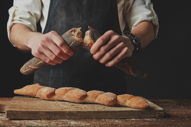 Handen breken en scheiden van verse biologische baguette