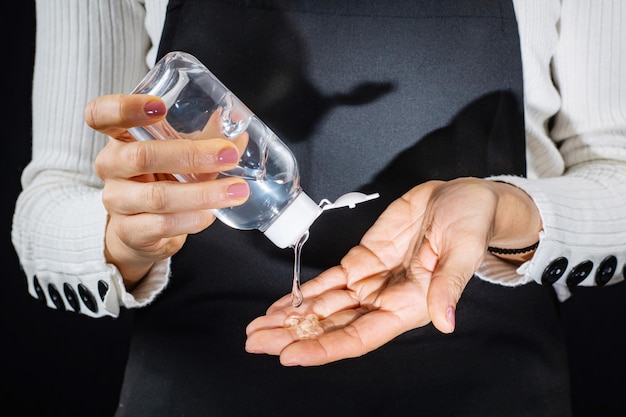 Handen desinfecteren met antimicrobiële gel op alcoholbasis Vrouw die gelontsmettingsmiddel op haar handen aanbrengt