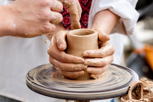 Handen die aan een pottenbakkersschijf werken en een aarden pot maken