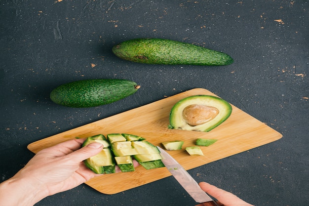 Handen die avocado op een scherpe raad snijden