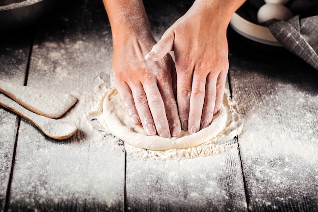 Handen die bakkerijdeeg in vlakke koek koken