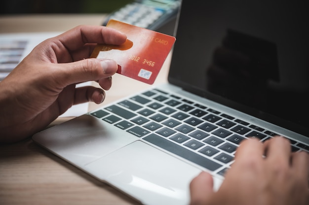 Handen die creditcard houden en laptop met behulp van. Online winkelen