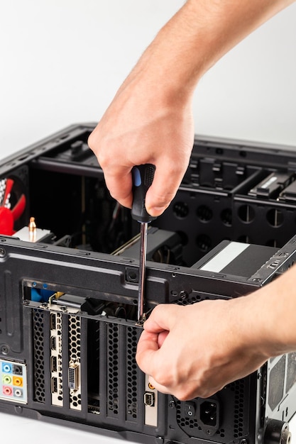 Handen die een beugel van een videokaart losschroeven terwijl u de hardware van de personal computer onderhoudt met selectieve focus