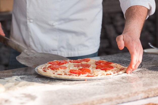 Handen die een pizza van de tafel