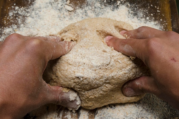 handen die een volkoren broodrol kneten