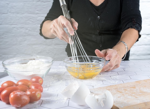 Handen die eieren kloppen met ingrediënten en keukengerei rond