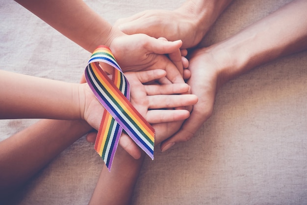 Handen die het vrolijke lint van de trotsregenboog voor LGBT-voorlichting houden