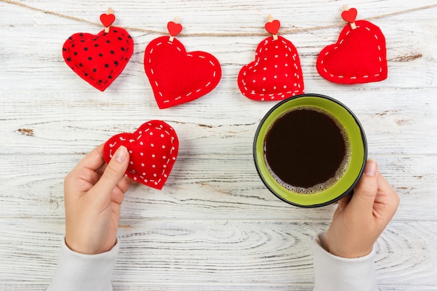 Handen die koffiekop en textielhart houden