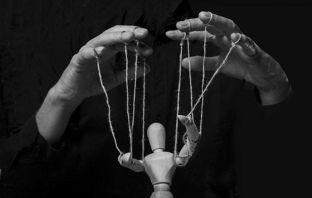 Foto handen die poppenspeler van marionet in actie manipuleren