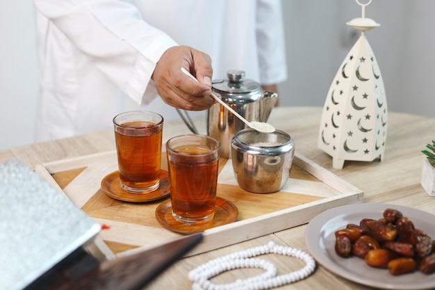 Handen die suiker toevoegen aan hete thee voor het ontbijt tijdens de Iftar Ramadan