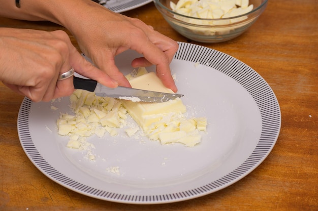 Handen die witte chocolade hakken om paaseieren te maken