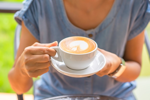 Handen die witte koffiekop met schotel houden.