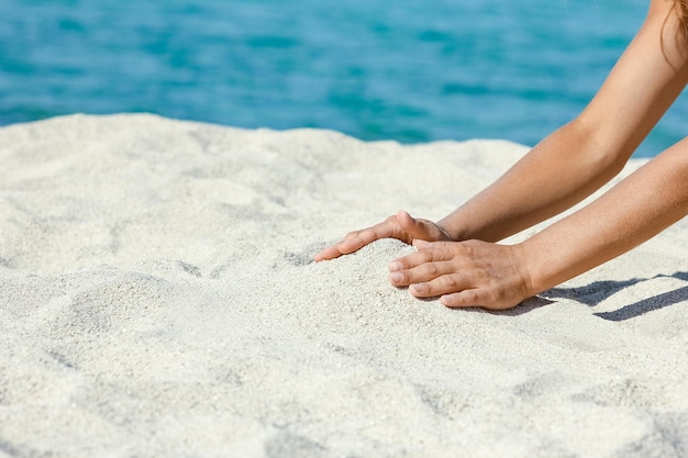 Handen die zand bij de kust gieten tijdens natuurreizen in het weekend