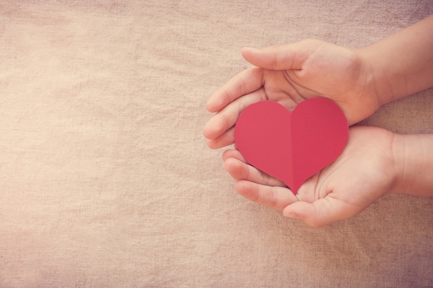 Handen en rood hart, ziektekostenverzekering, donatie en liefdadigheidsconcept, wereldhartdag