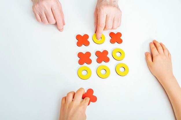 Handen grootmoeder en kleinzoon spelen tic-tac-toe houten bordspel