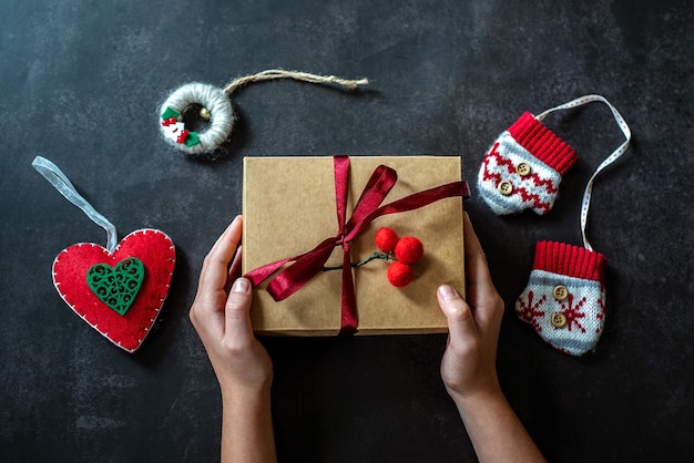 Handen houden de doos van de gift van Kerstmis op donkere backround, de doos van de nieuwjaarsgift in de handen van het kind, Kerstdecoratie