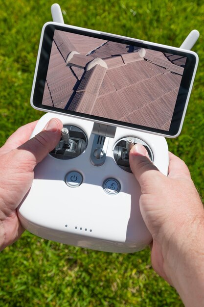 Handen houden drone quadcopter controller met residentiële dak beeld op het scherm