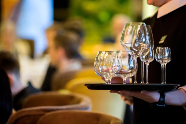 Handen houden een dienblad met glazen Ober op de achtergrond van het restaurant