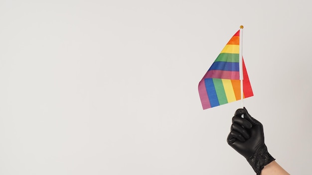 Handen houden een regenboogvlag Handen dragen zwarte latex handschoenen