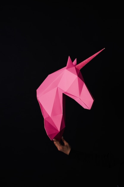 Handen houden een roze Eenhoorn. Artwork. 3d papercraftmodel van een eenhoorn. Ruimte kopiëren