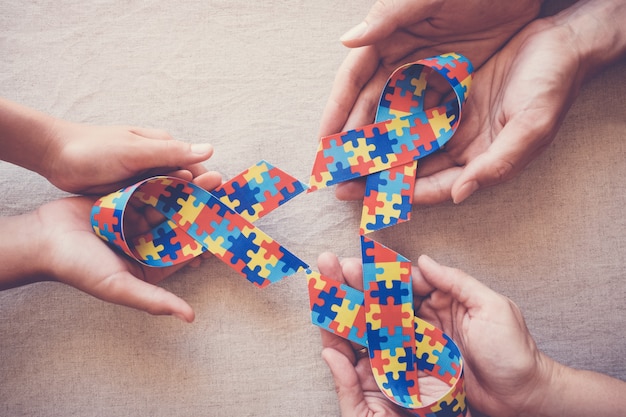 Handen houden puzzellint vast voor bewustwording rond autisme