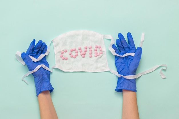 Handen in medische handschoenen houden het masker op een lichte achtergrond Voorkoming van de verspreiding van het coronavirus