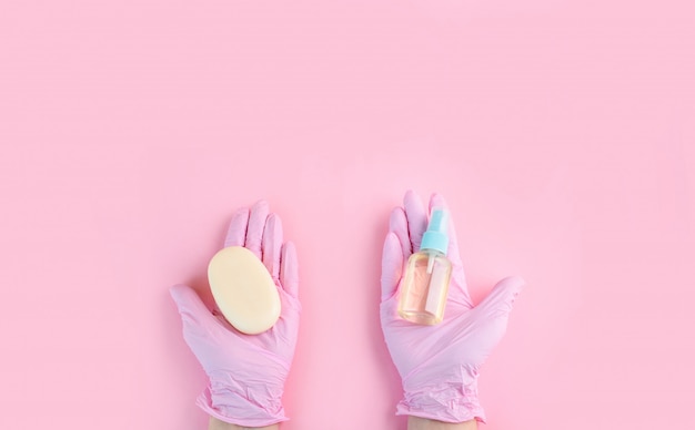 Handen in medische handschoenen liggen op een roze achtergrond.