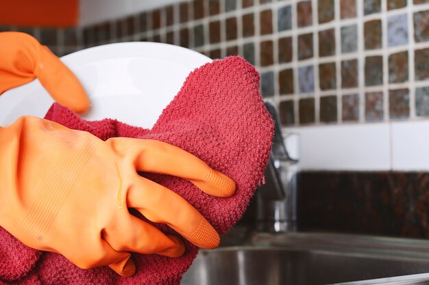 Handen in rubberen handschoenen afwassen met spon