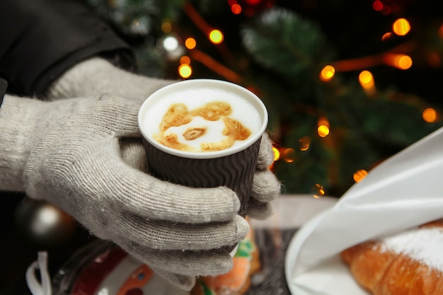 Handen in wanten houden een warme kop koffie vast. Koffie voor in de winter.
