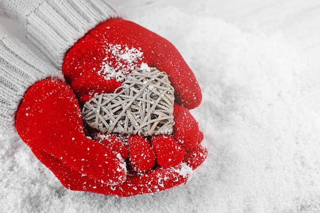 Handen in warme rode handschoenen met rieten hart op sneeuw